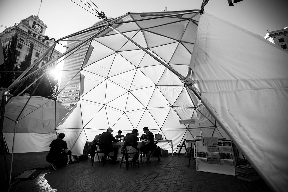 Black and white image of people at a table inside of a geodesic dome