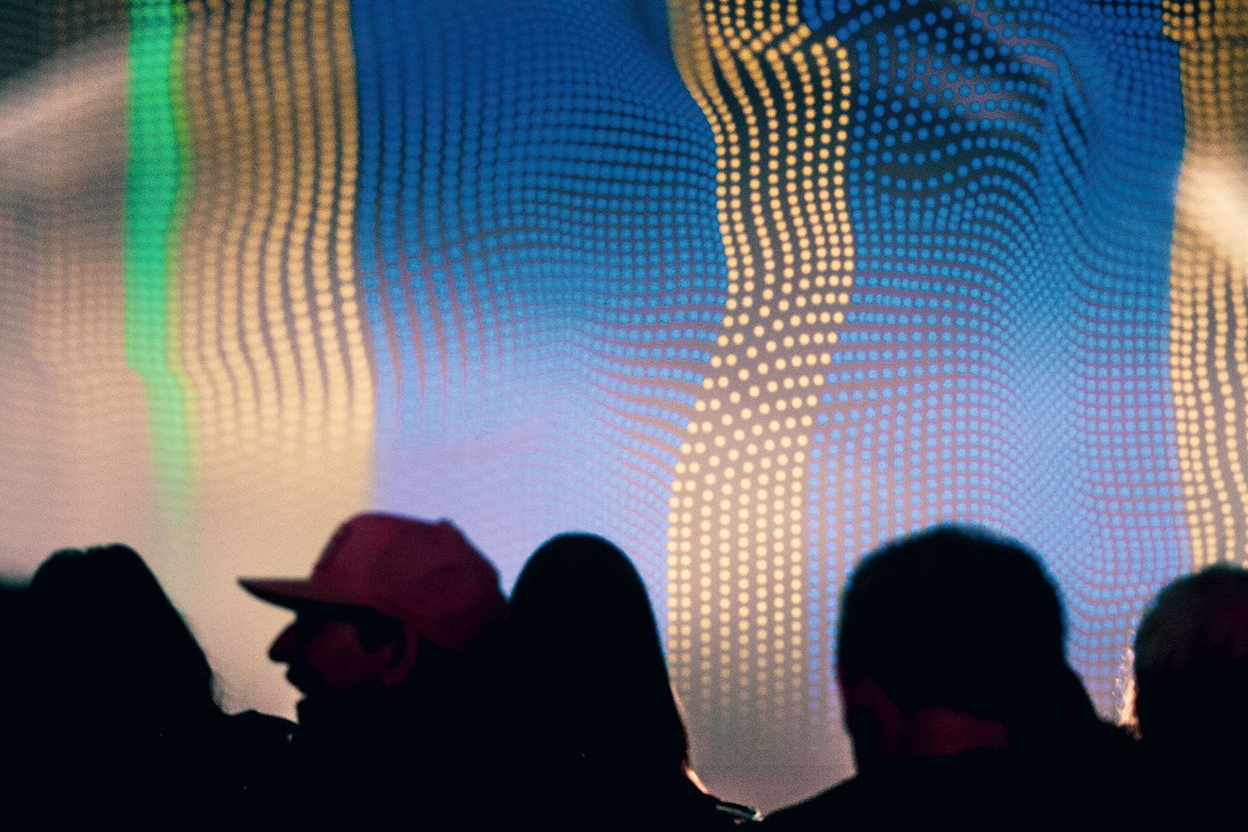 Crowd of people in silhouette infront of abstract projection